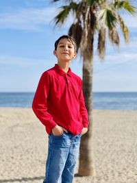 Portrait of young man standing at beach against sky by the beach 