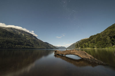 Scenic view of lake and mountains against sky at night