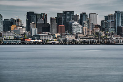 Modern buildings by sea against sky in city