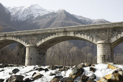 Arch bridge over snowcapped mountains against sky