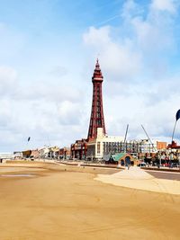 Beach by buildings in city against cloudy sky