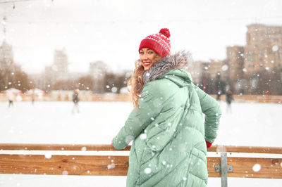 Portrait of smiling young woman wearing knit hat standing outdoors