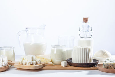 Dairy products in glass recipients and wooden dishes on white background.