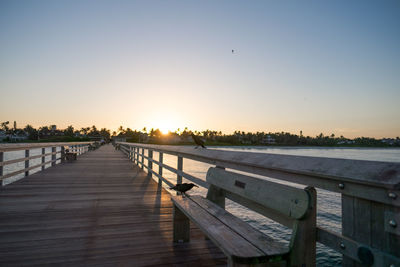 Pier over lake against clear sky during sunset