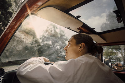 Young man looking up through windshield while sitting in van