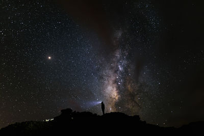 Silhouette of a mountaineer looking at the milky way