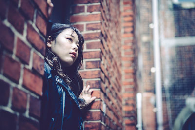 Portrait of woman standing against brick wall