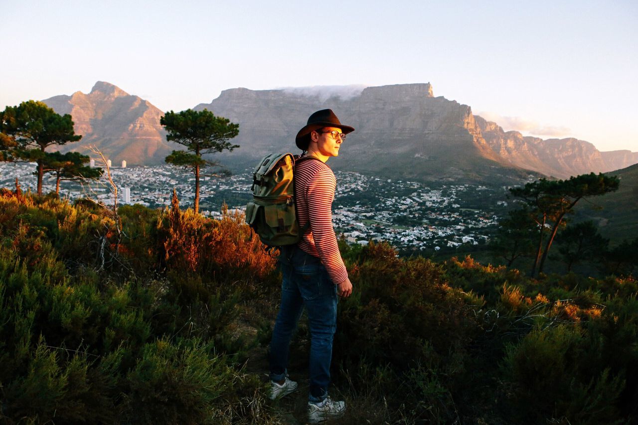 mountain, lifestyles, leisure activity, casual clothing, standing, full length, rear view, mountain range, tranquil scene, tranquility, beauty in nature, three quarter length, scenics, nature, young adult, water, clear sky, sky