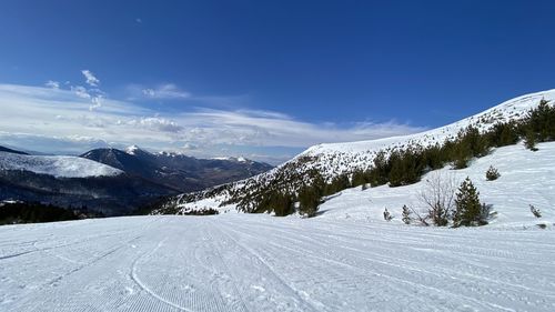 Scenic view of snow covered mountains against blue sky