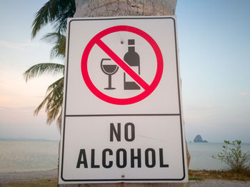 Close-up of road sign by sea against sky