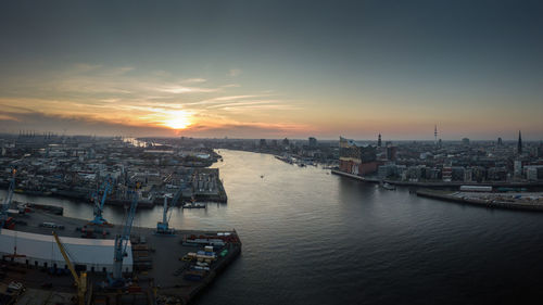 High angle view of river and buildings against sky at sunset