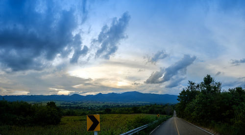 Panoramic shot of road amidst trees against sky