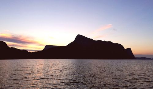 Silhouette rocks by sea against sky during sunset
