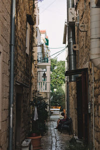 Rear view of people sitting in alley amidst buildings