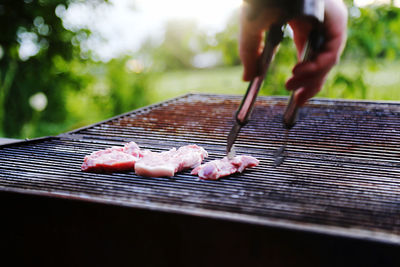 Cropped hand of man preparing food on grill 