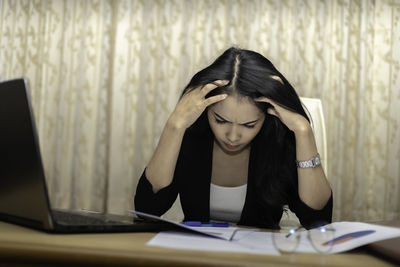 Woman looking at camera while sitting on table