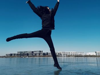 Man jumping in swimming pool against clear blue sky