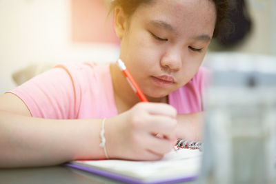 Asia young girl learning online at home with wring book