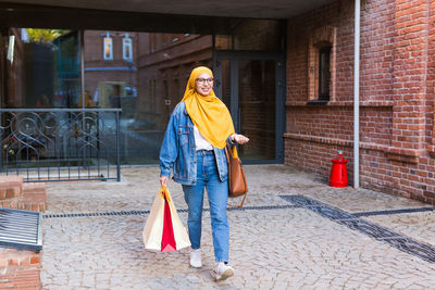 Portrait of smiling woman standing against building