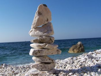 Stack of stones on beach against clear sky