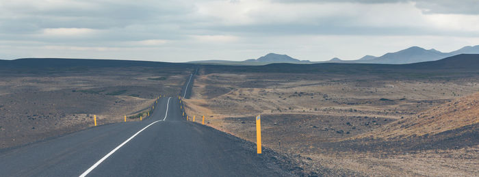 Road leading towards mountains against sky