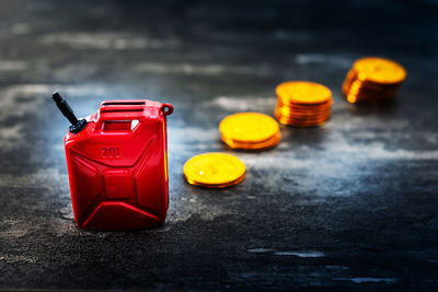 High angle view of miniature red gasoline gallon and gold coins on table