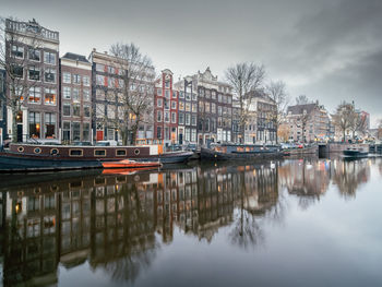 Scenic view of river by buildings against sky