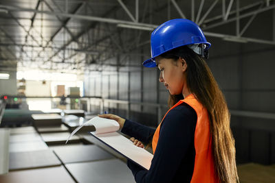Female worker checking documents in factory warehouse