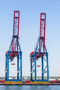 Cranes at commercial dock against sky