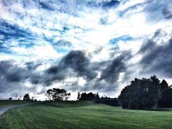 Scenic view of grassy field against cloudy sky