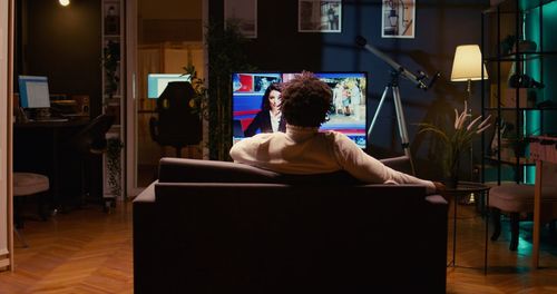 Rear view of woman sitting on chair at home