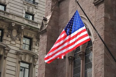 Low angle view of american flag against buildings in city