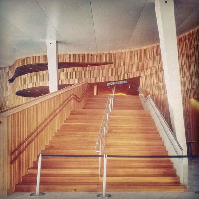 indoors, the way forward, empty, built structure, lighting equipment, architecture, absence, railing, illuminated, in a row, ceiling, wood - material, diminishing perspective, architectural column, chair, no people, vanishing point, corridor, long, column