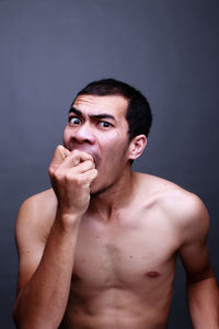 Portrait of shirtless man against gray background