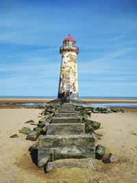 Lighthouse on beach against sky