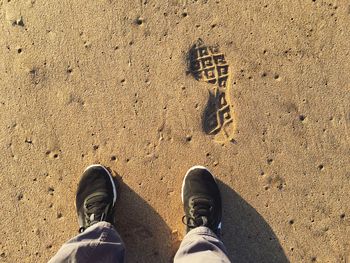 Low section of man standing on sand