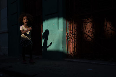 Woman standing against wall at night