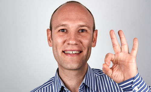 Portrait of smiling man gesturing against gray background