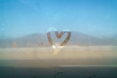 Close-up of heart shape on wet glass