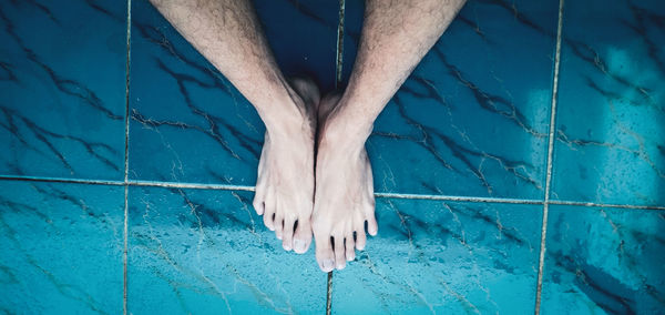 Low section of person standing by swimming pool