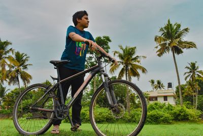 Boy standing with cycle and looking to the sky. concept with copy space. solo outdoor activities.