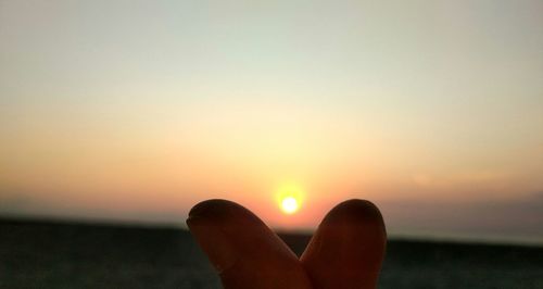 Low section of woman against sun during sunset