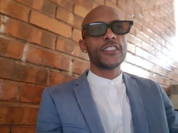 Portrait of young man wearing sunglasses against brick wall