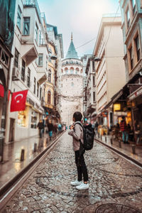 Rear view of woman walking on street amidst buildings in city