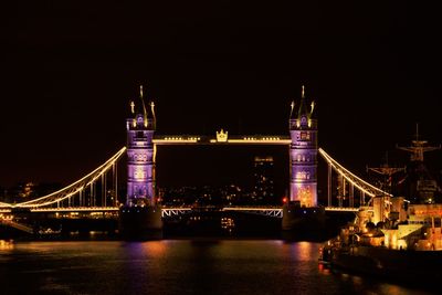 Illuminated suspension bridge over river at night