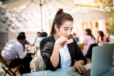 Woman using phone while sitting on table