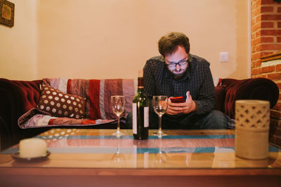 Young man using phone while sitting on table