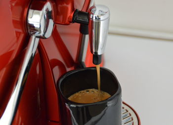 Close-up of machine pouring coffee in cup at cafe