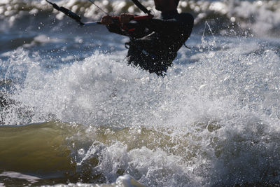 Midsection of man kiteboarding in sea