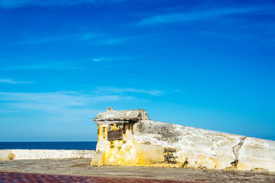 Castle by sea against blue sky on sunny day